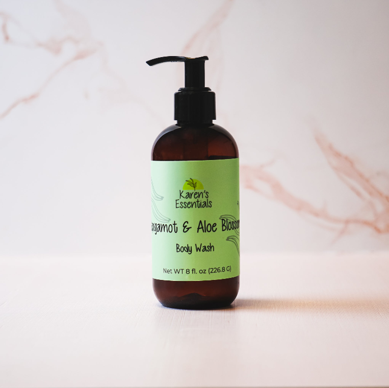 a black bottle with a dark brown tint with a green label on it, black text of the company name Karen Essentials, Bergamot & Aloe Blossom Body Wash, Net WT 8 fl. oz