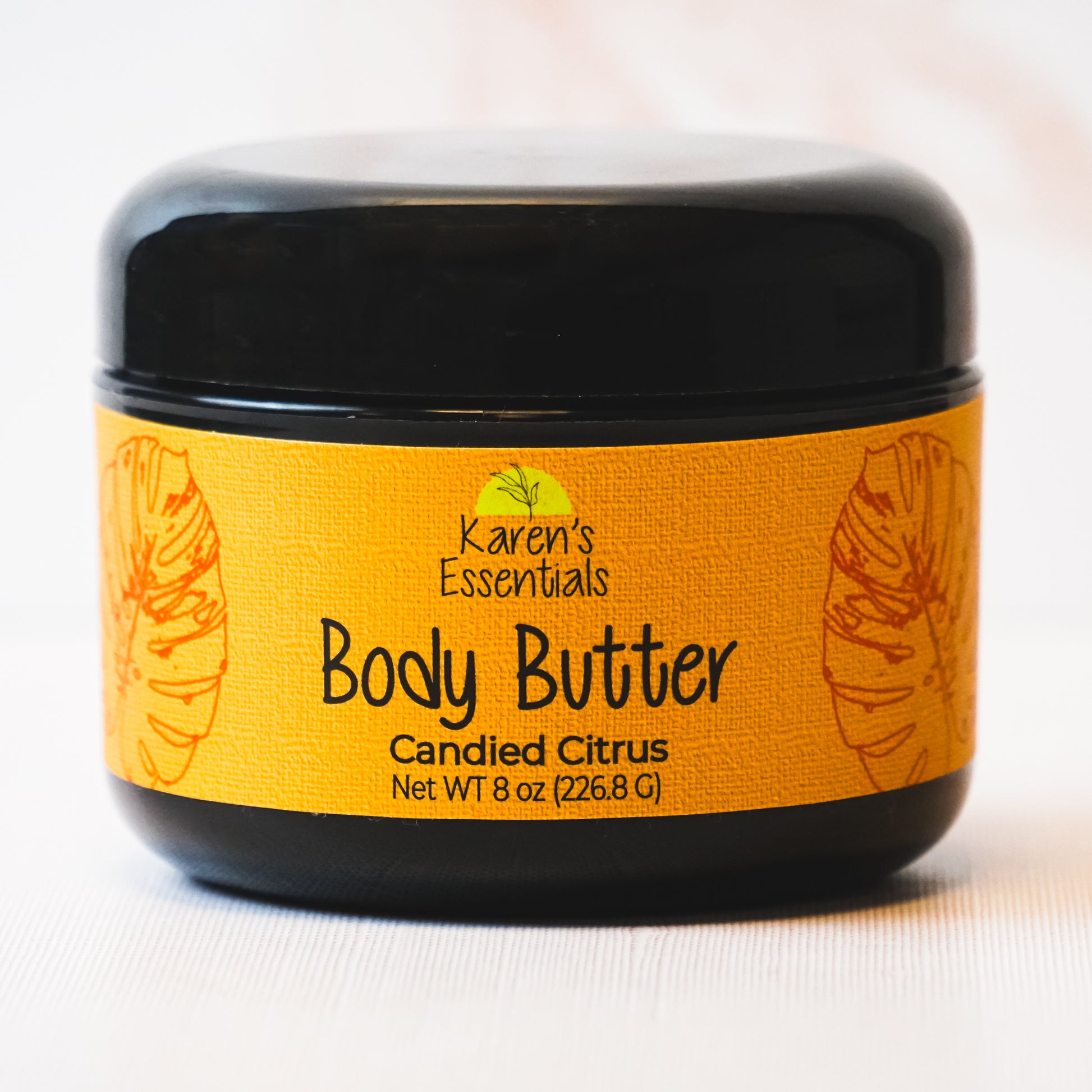 picture of a black container featuring a gold label with black text stating Karen Essentials, the company name, the container is Body Butter with the scent of Candied Citrus in a 8 oz container 