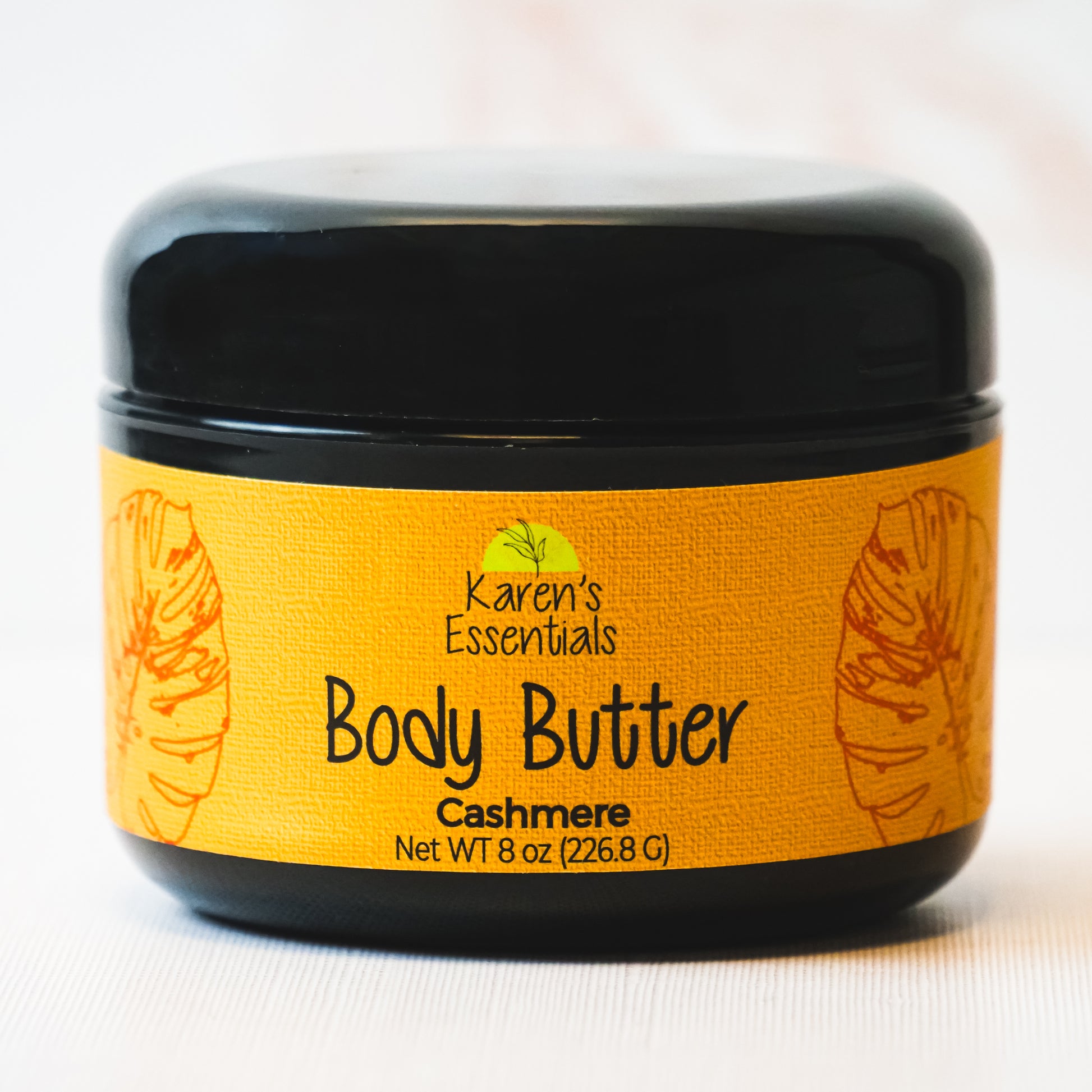 picture of a black container featuring a gold label with black text stating Karen Essentials, the company name, the container is Body Butter with the scent of Cashmere in a 8 oz container 